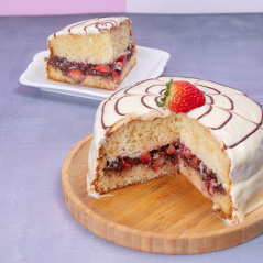 Bolo branco com morango no topo e recheio de frutas vermelhas